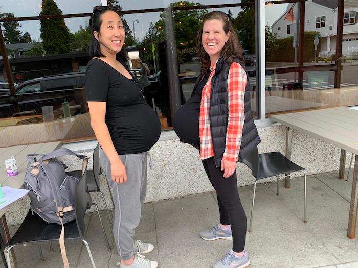 Pregnant mom friends Hee Yon and Kara smile for a photo.