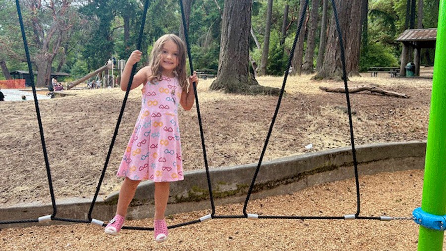 Young girl climbs the rope bridge at the Lincoln Park playground in West Seattle