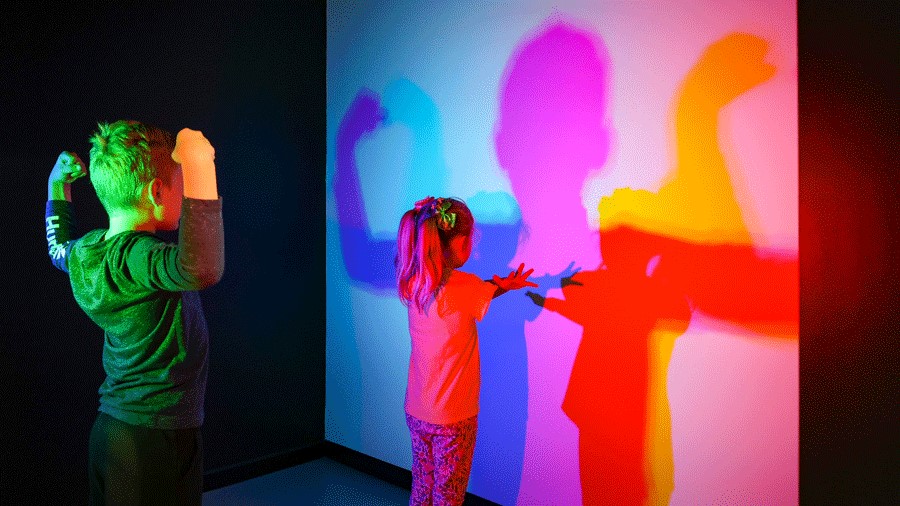 Two young kids strike a pose in the color room at Museum of Illusions