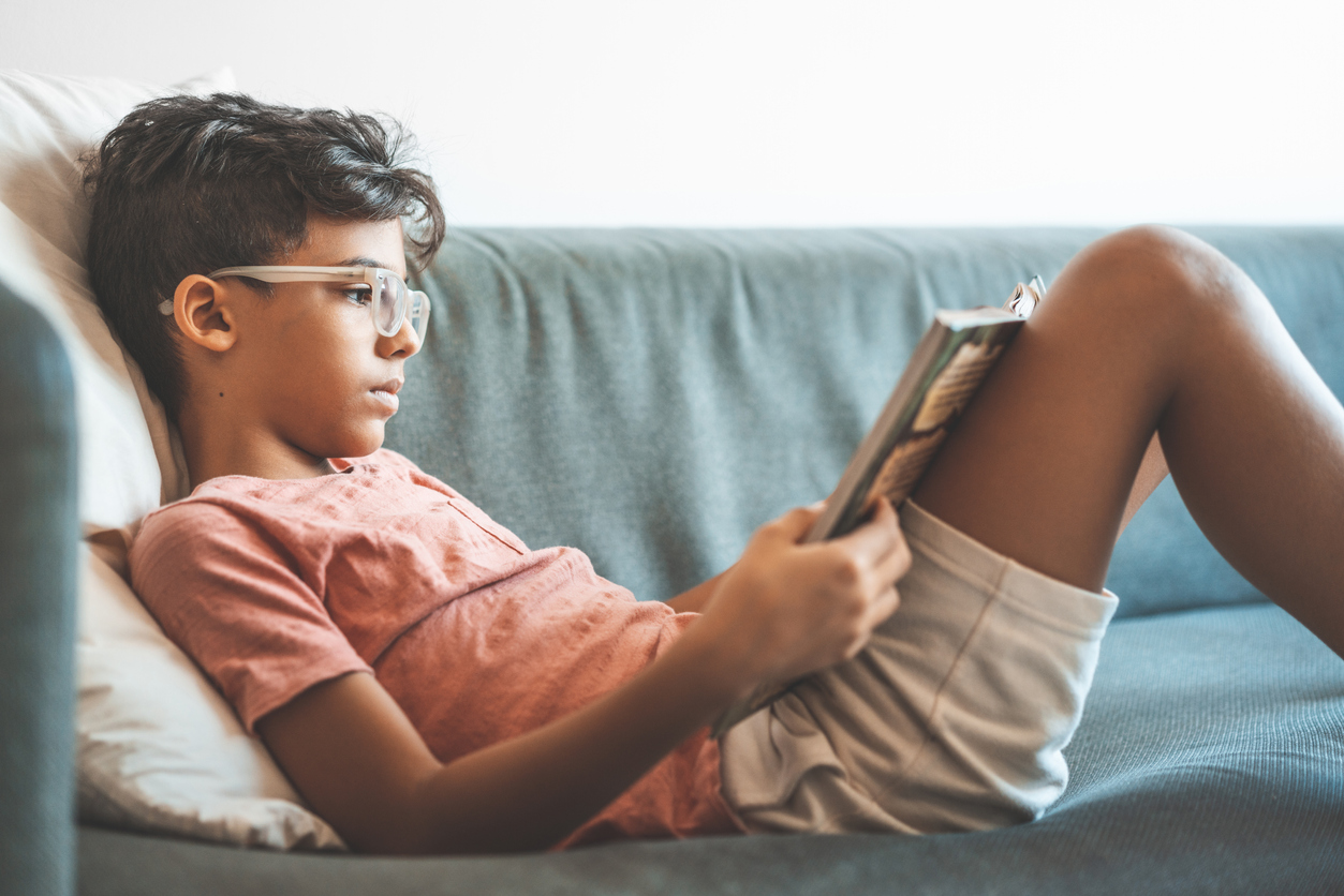 tween boy reading a book on the couch seattle area library summer reading programs for kids and families
