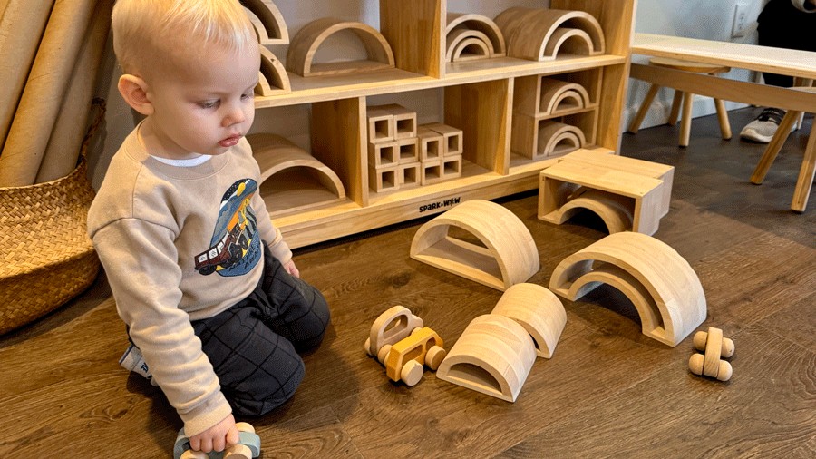 toddler playing with wooden cars at an indoor play place in Enumclaw