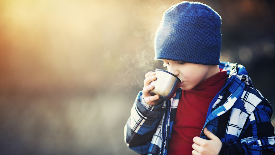 boy eating a warm lunch on a cold winter day