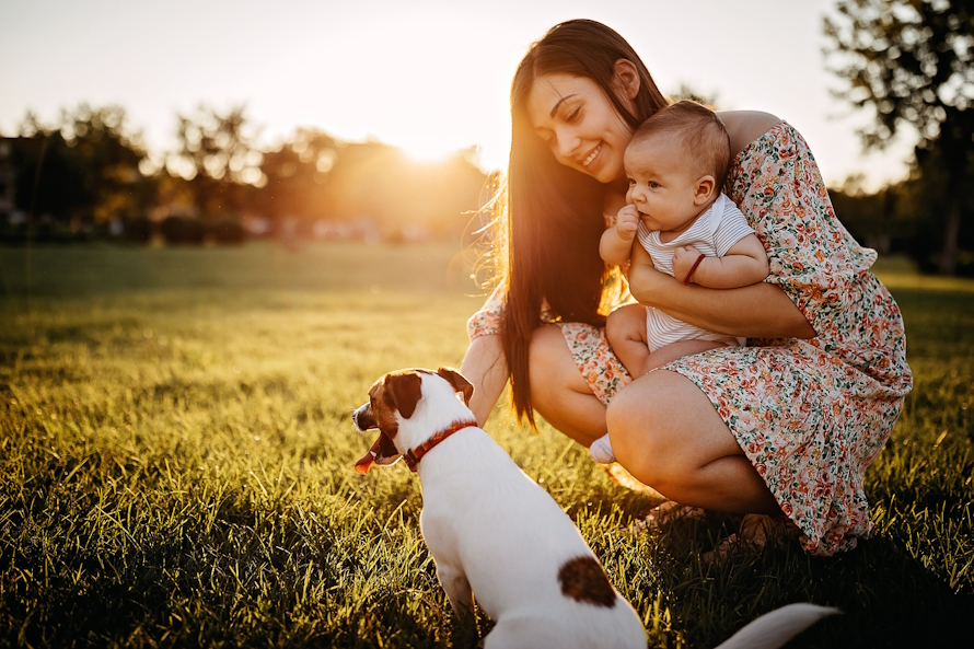 Woman holding a baby petting a small dog
