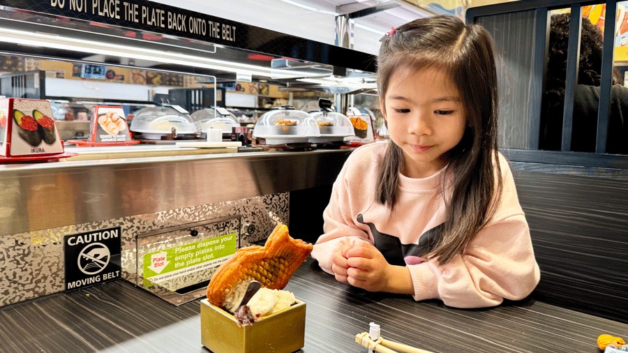 Young girl with ice cream dessert at Kura Sushi, a family-friendly Seattle-area restaurant that makes for a fun fall activity