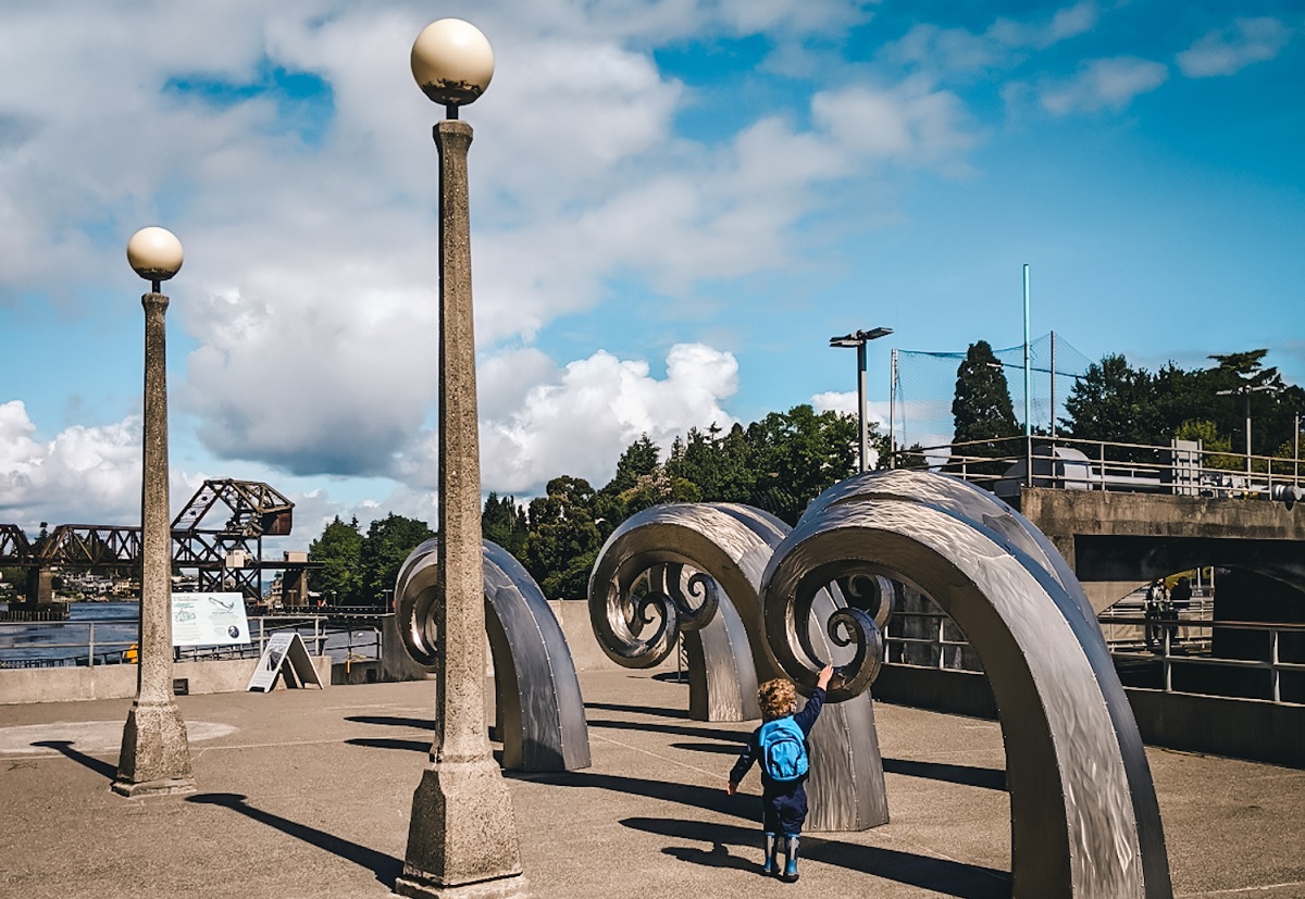 Kids play by the wave sculptures on the fish ladder side of the Ballard Locks