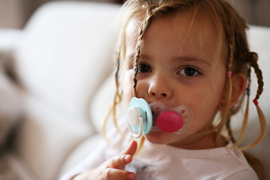 little girl with two pacifiers
