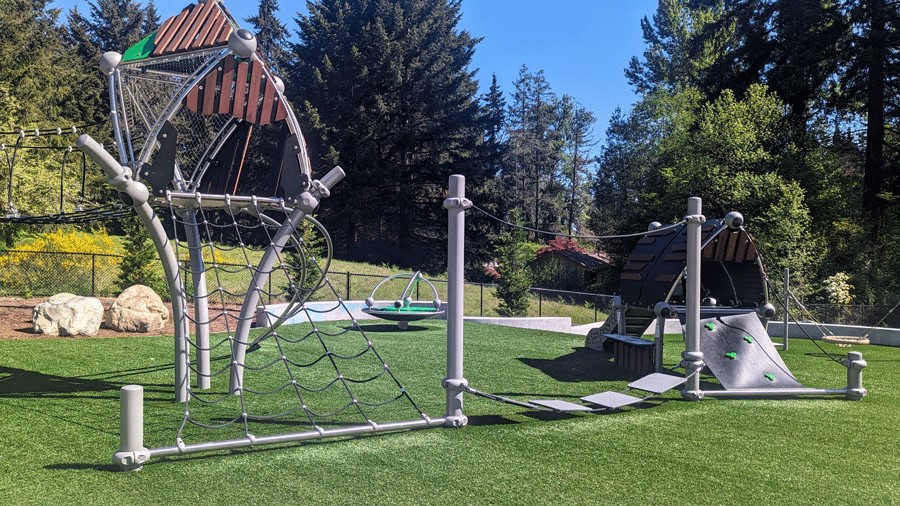 A rope ladder leads down to a floating bridge, connecting the big-kid play area to the tot play structure