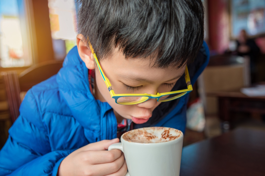 Young boy drinking hot chocolate at a kid-friendly coffee shop