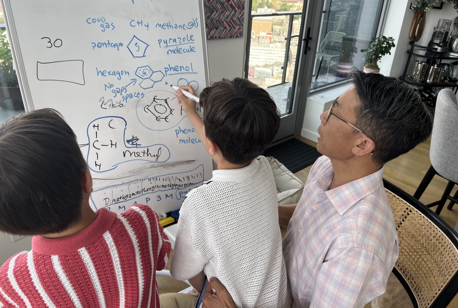 Moy and his sons using a white board to learn at home