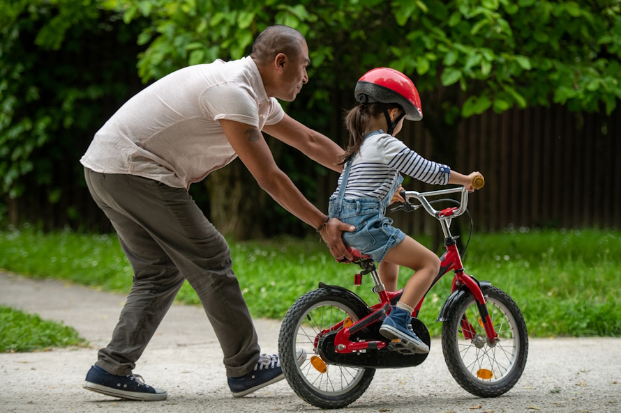 Girl learning to ride a bike with a properly fitted helmet