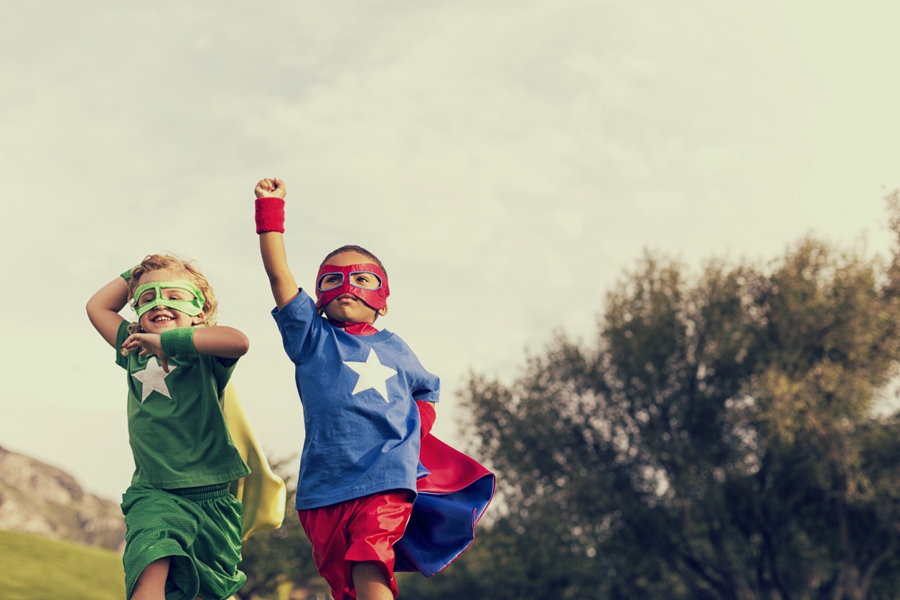 Two little boys dressed in superhero costumes outside
