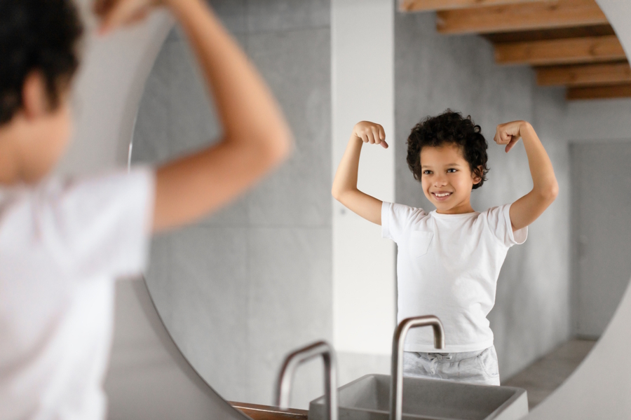 Childing looking in a mirror doing a power pose