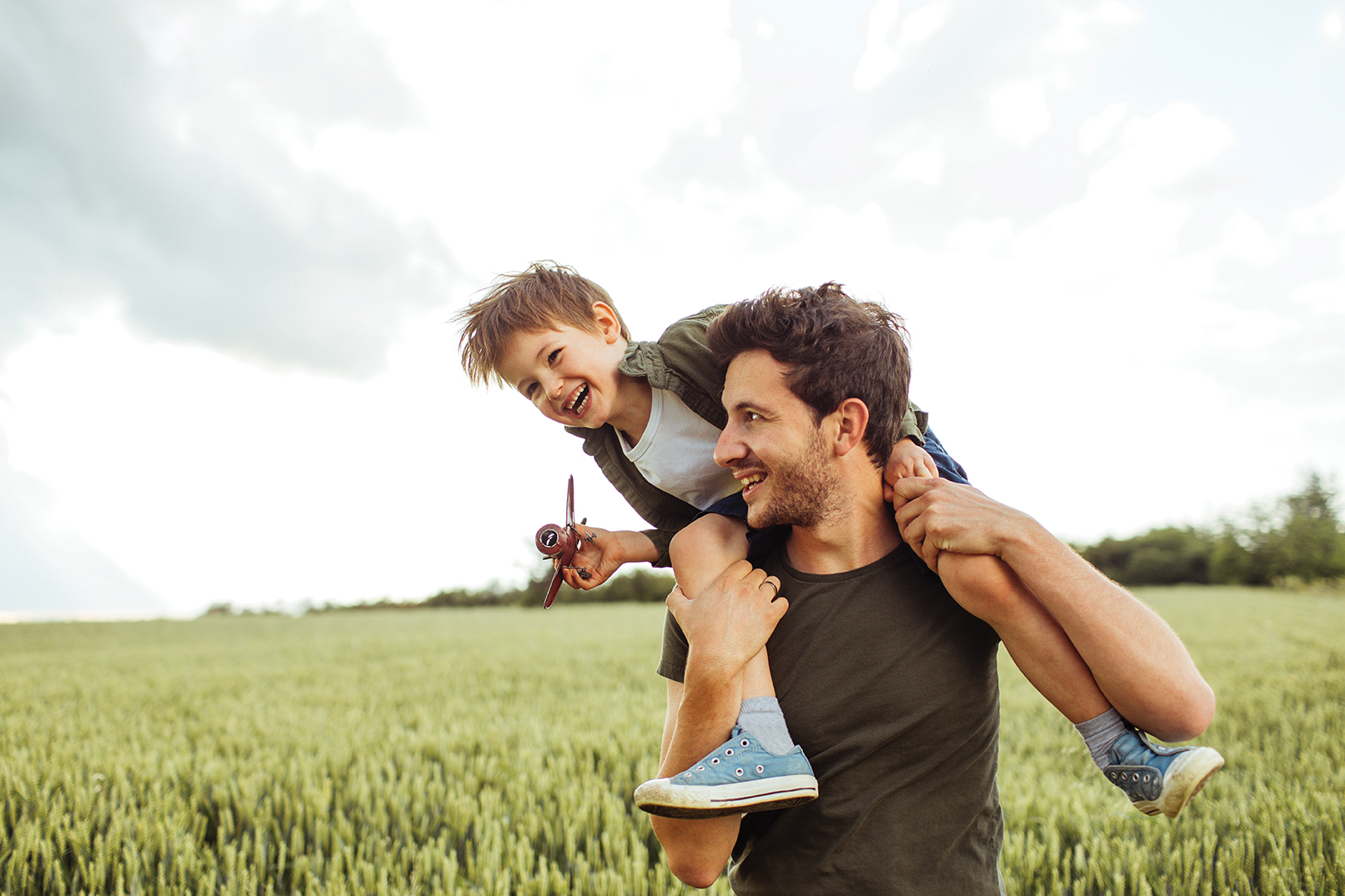Dad with child on his shoulders in a grass field