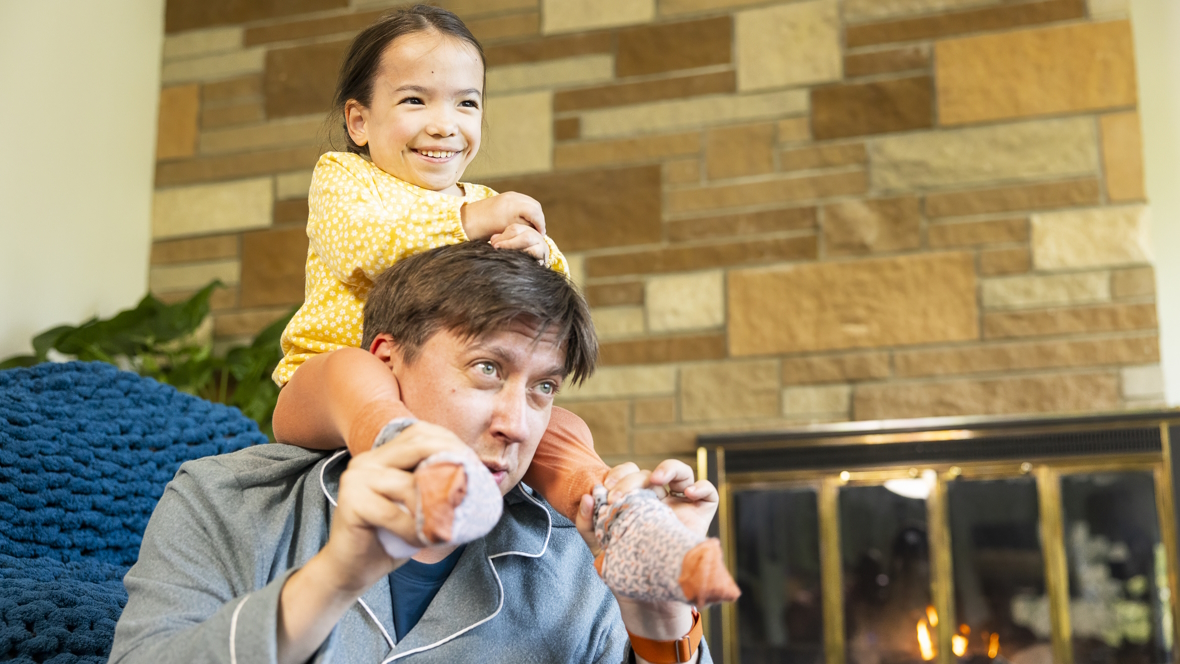 Child smiling and sitting on her father's shoulders