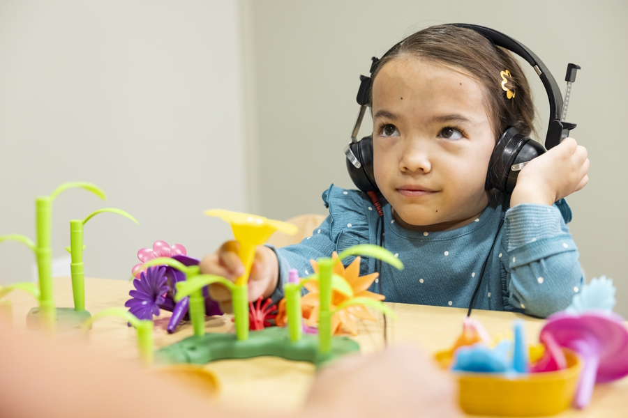 Hailee wearing headphones and playing with toys at a table
