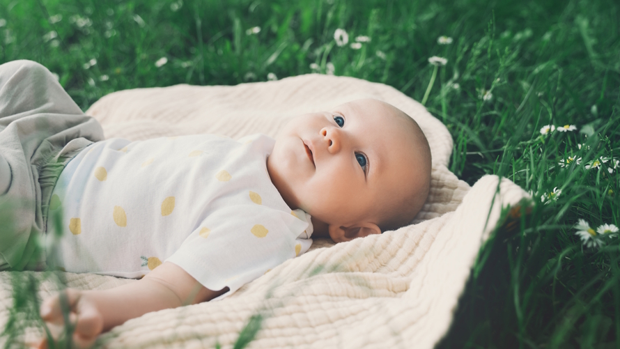 Baby with an April birthday laying in the grass with a cute spring baby name