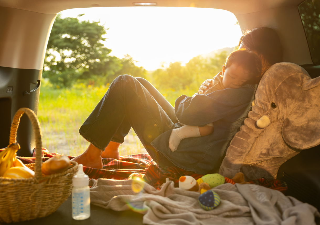 a parent and baby enjoy the summer sunset while car camping