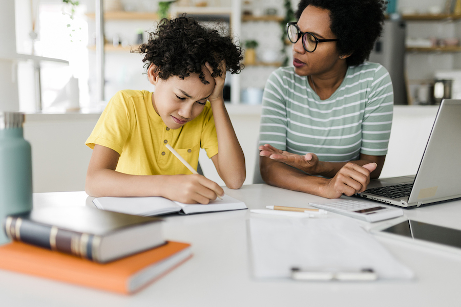 boy frustrated with math homework while being supported by his mom