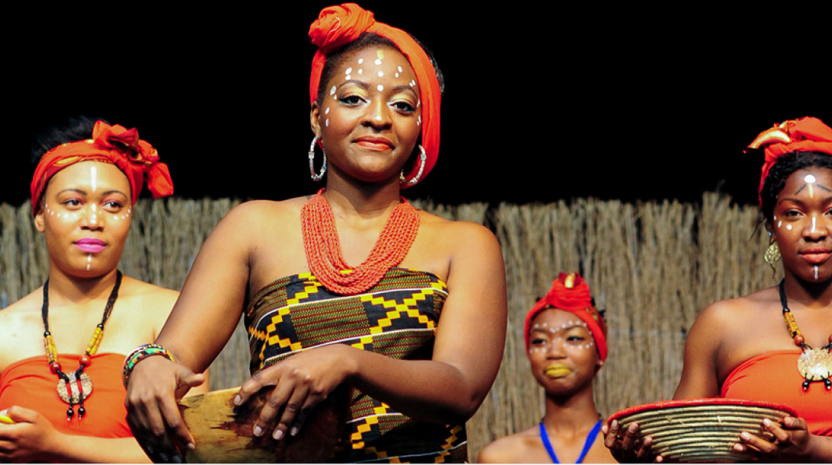 Four women wearing traditional African clothing and face paint