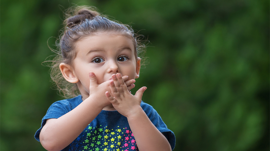 Young girl with hands over mouth