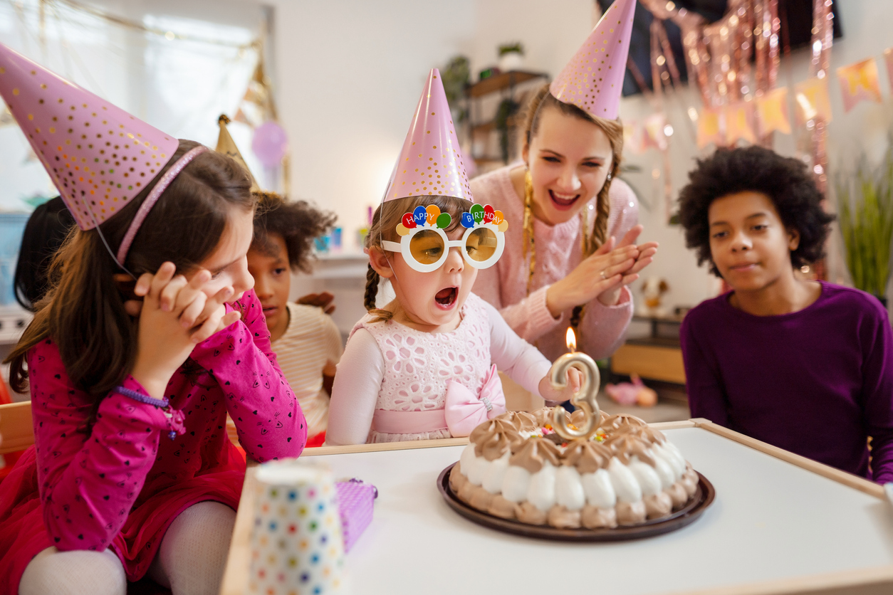 Little girl blowing out birthday candles at birthday party