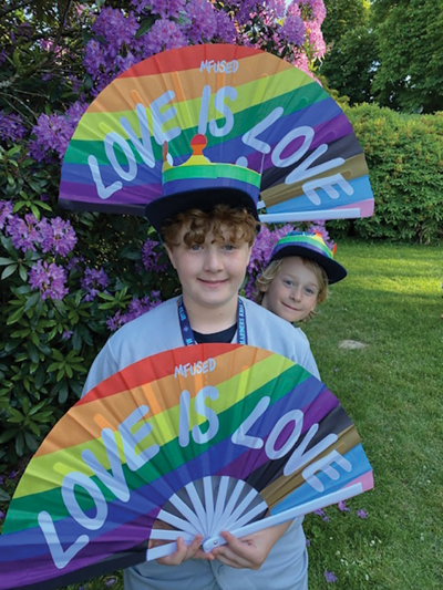 Two kids holding rainbow fans that say 'love it love'