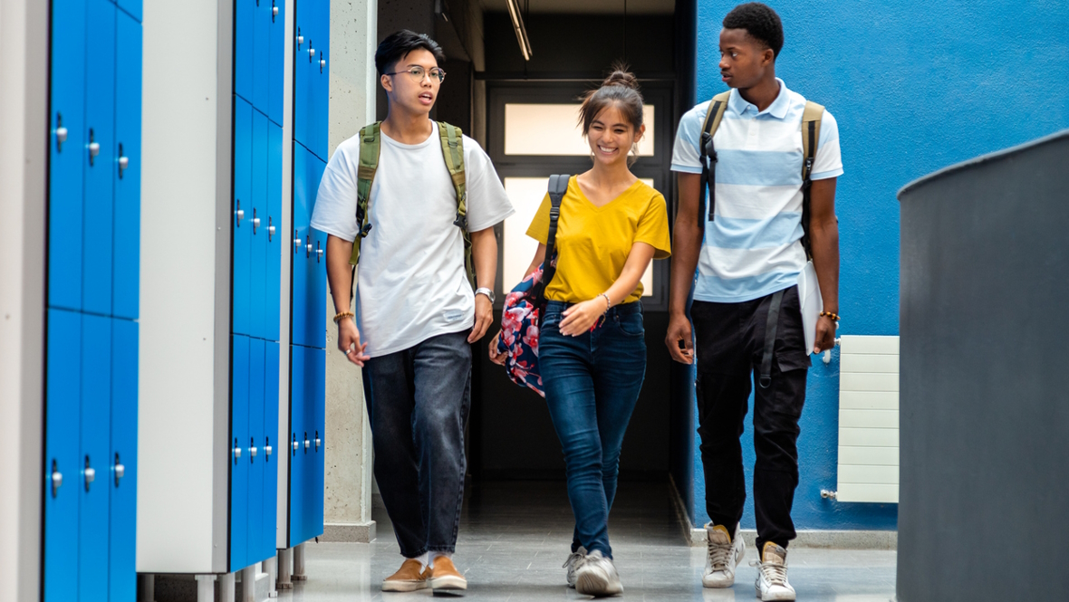 Three high school students walking down a school hallway