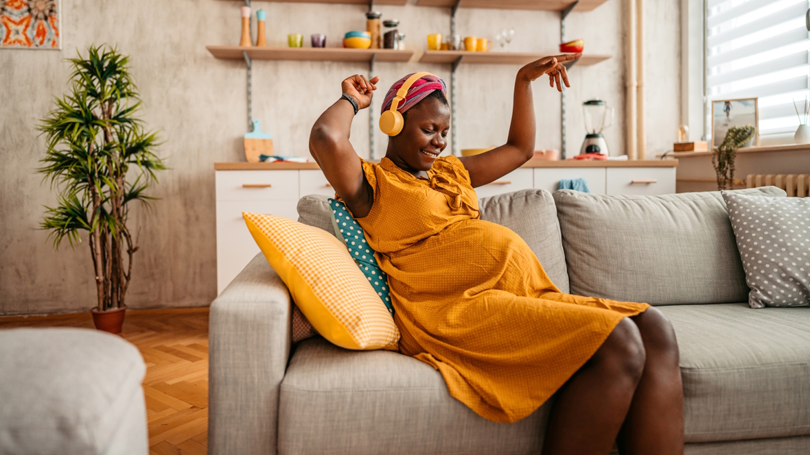 pregnant mom on a couch listening to music about parenthood by Black icons