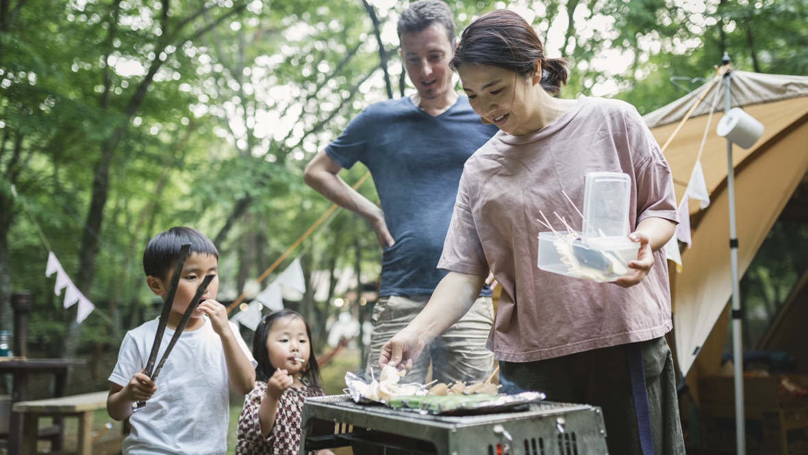 family cooking dinner over a stove at a camp ground