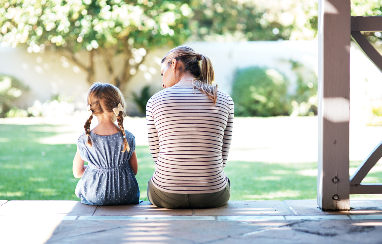 mother and daughter sitting side by side on the back porch with their backs to the camera