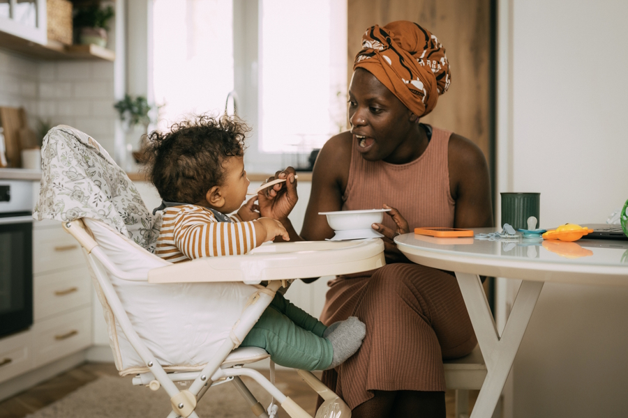 Mom feeding a baby in a high chair to help wean to solid foods