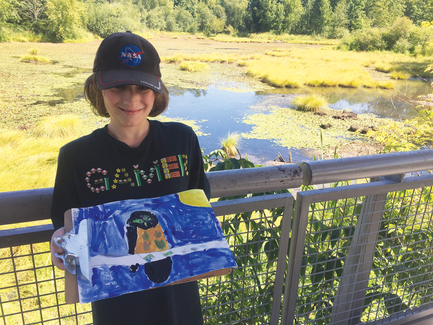 Boy outdoors proudly holding painting of a bird best nature crafts and walks for kids and families around Seattle
