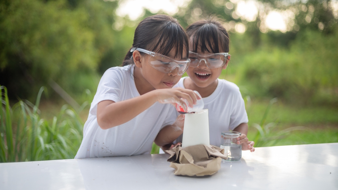 two girls doing science experiments outside with baking soda and vinegar