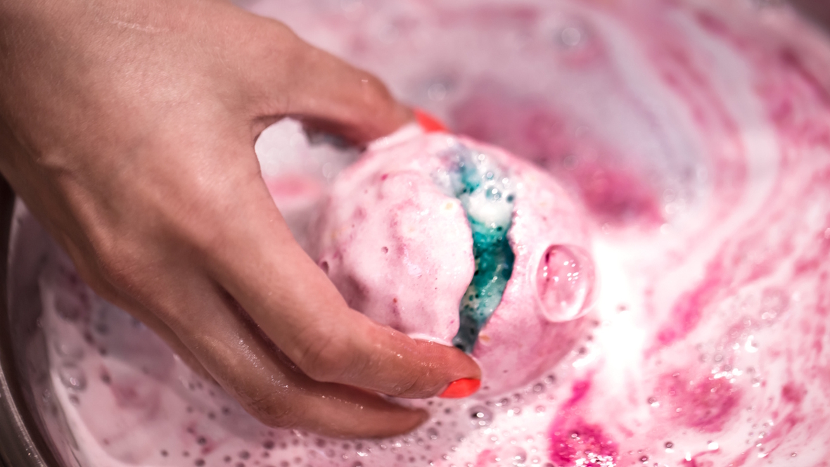 a pink and white bath bomb melting with something green inside