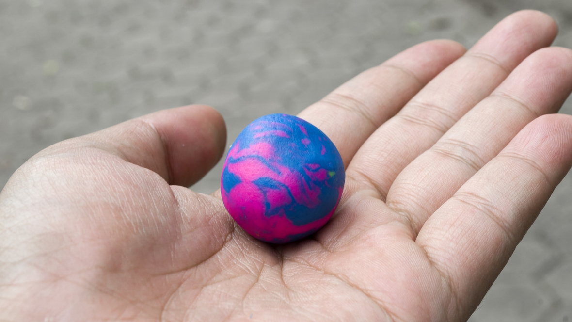 an open palm hand holding a purple and blue ball