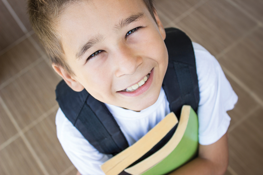 boy holding books and smiling