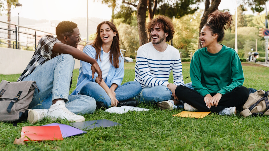 group of college students sitting on the grass at a college campus