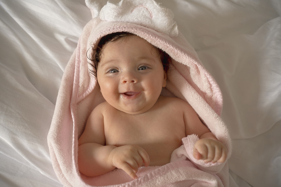 baby with a pink blanket smiling 