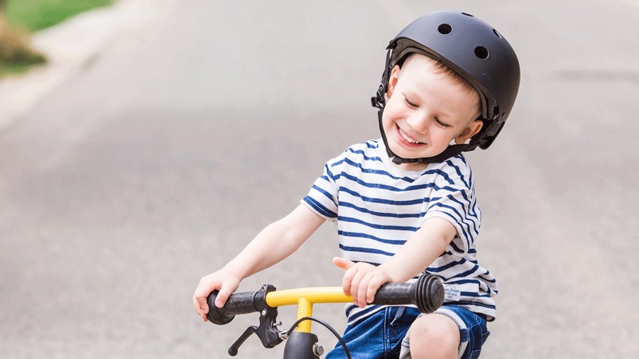Young boy wearing a bike helmet smiling on his bike at a Seattle-area pump track