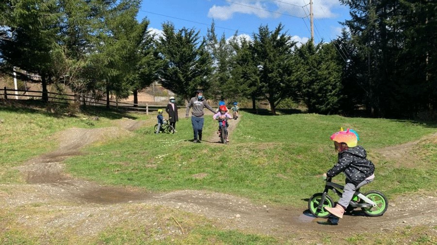 Young girl wearing a bike helmet tries out the pump track at Fisher Creek Park, a Seattle-area pump track