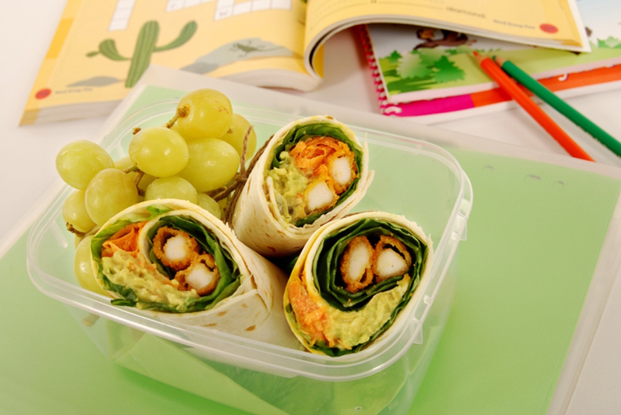 lunch wraps in a plastic container with some grapes