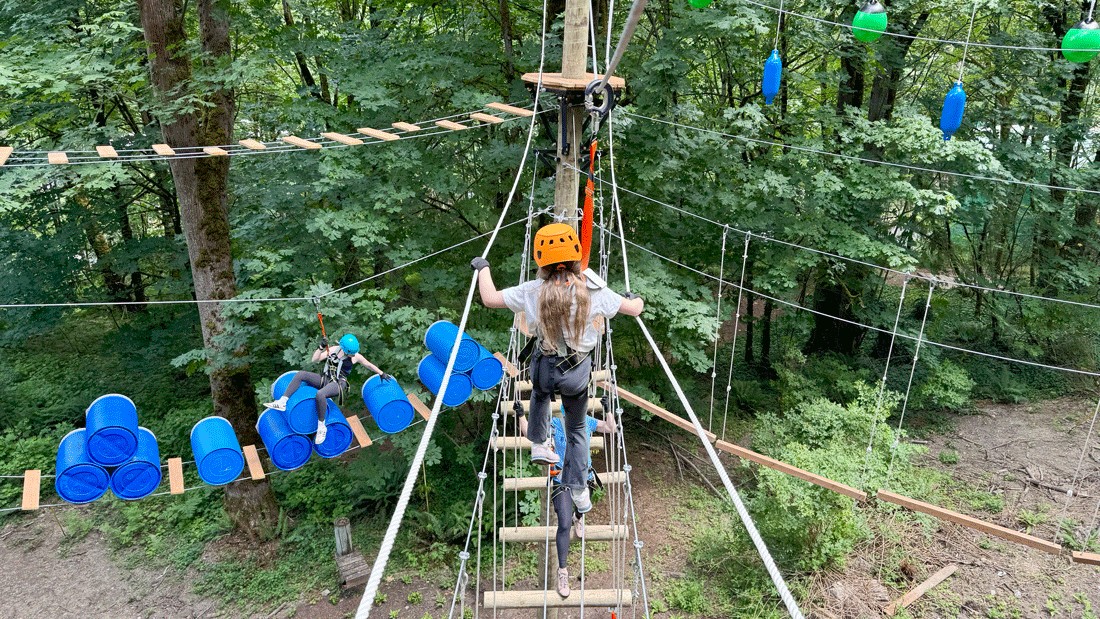 girl climbing across bridge on the ropes course at Bellevue Adventures Aerial Park