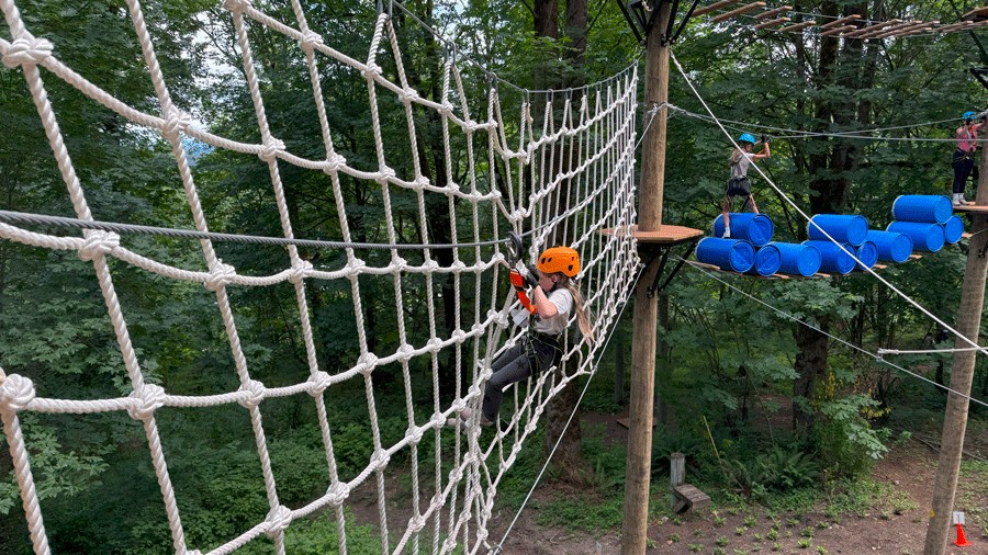 young girl climbing across rope net at Bellevue Adventures