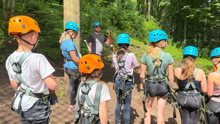 group of kids at Aerial Park listening to safety guidelines, with helmets and harnesses