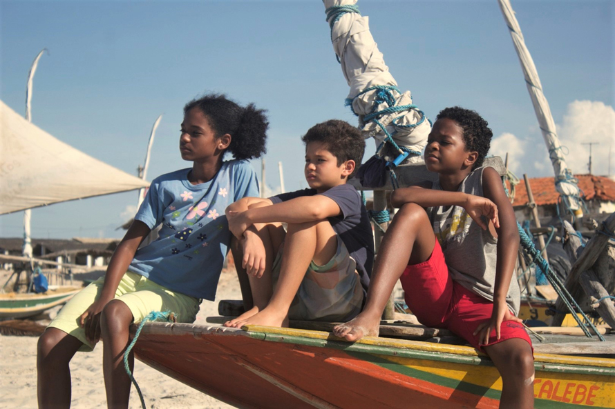 young warriors 1 childrens film festival still image of three kids sitting on the prow of a small boat on the beach