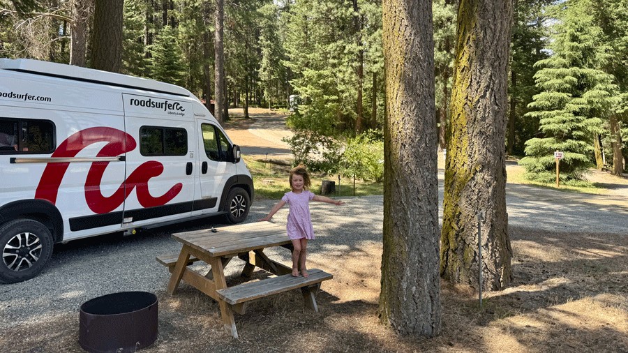 young kid posing in front of a campervan rental in idaho during a family road trip