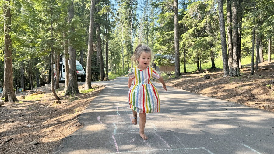 young child playing hopscotch at a Priest Lake campsite in Idaho on a family camping trip