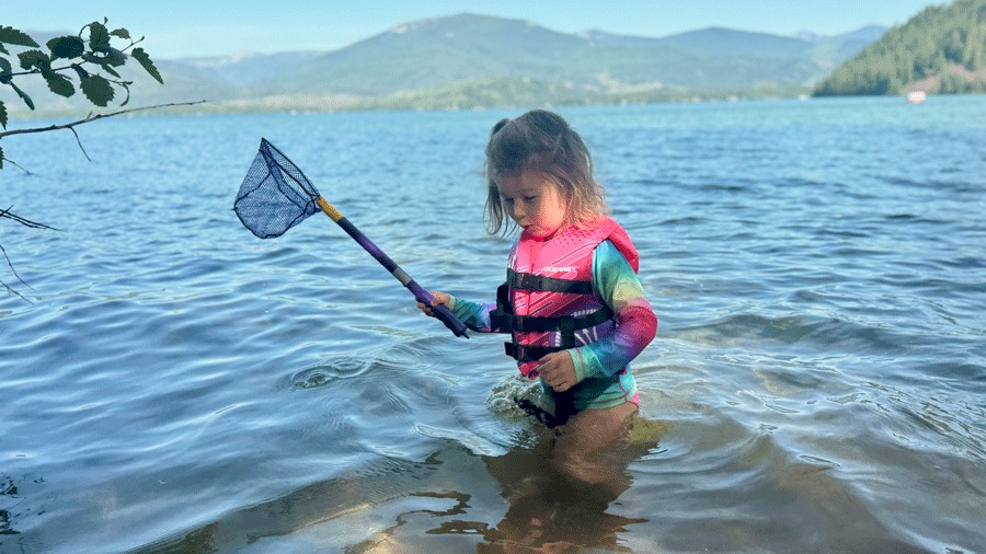young child in a life jacket fishing in Priest Lake on a camping trip