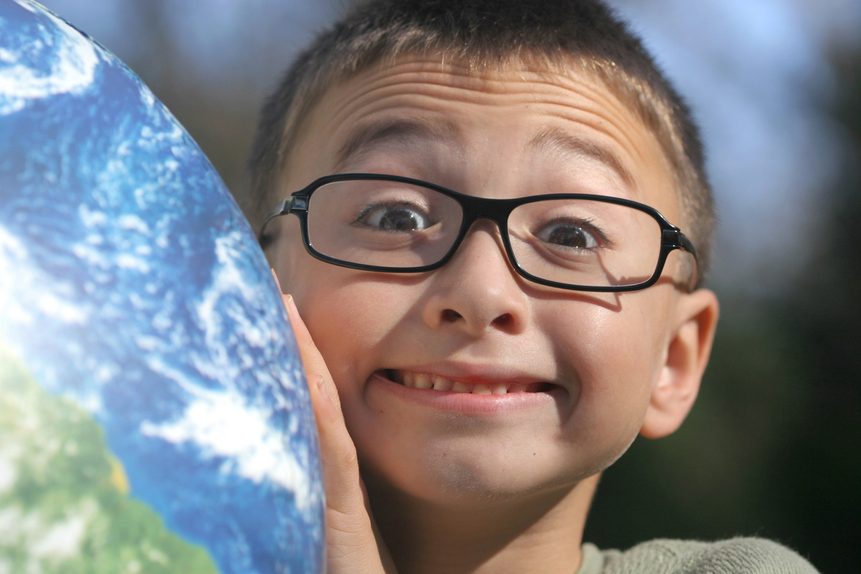 Cute boy with glasses holding up a globe