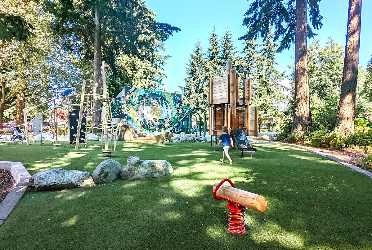A young boy runs across the turf toward new playground equipment and a mural by artist Gabrielle Abbott at South Lynnwood Park